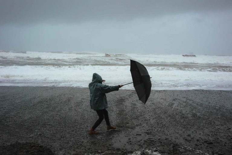 Une personne se promenant sur la plage un jour de pluie